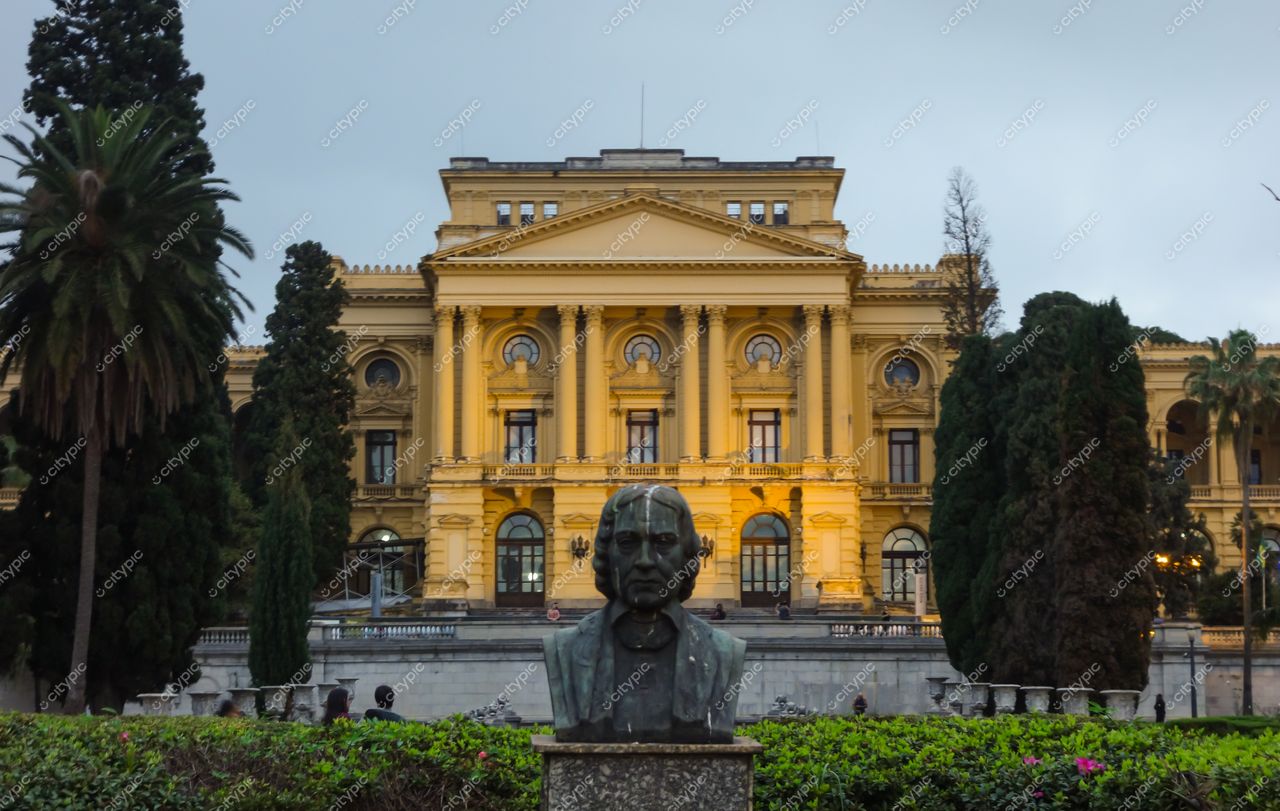 São Paulo, São Paulo, fachada de edifício histórico iluminada ao crepúsculo com escultura e vegetação exuberante