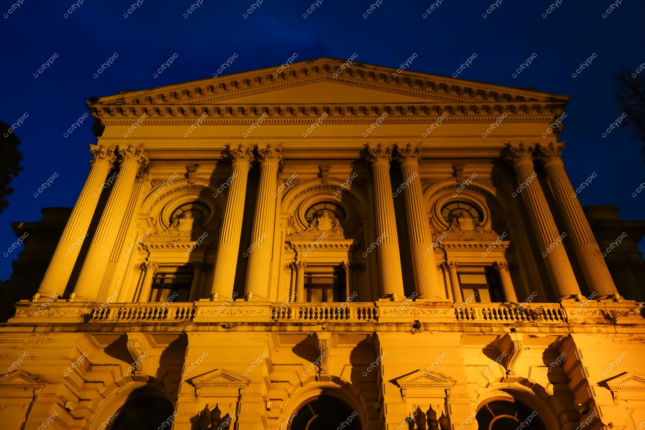 São Paulo, São Paulo, fachada de edifício histórico neoclássico iluminado em laranja sob céu noturno azul sem tráfego