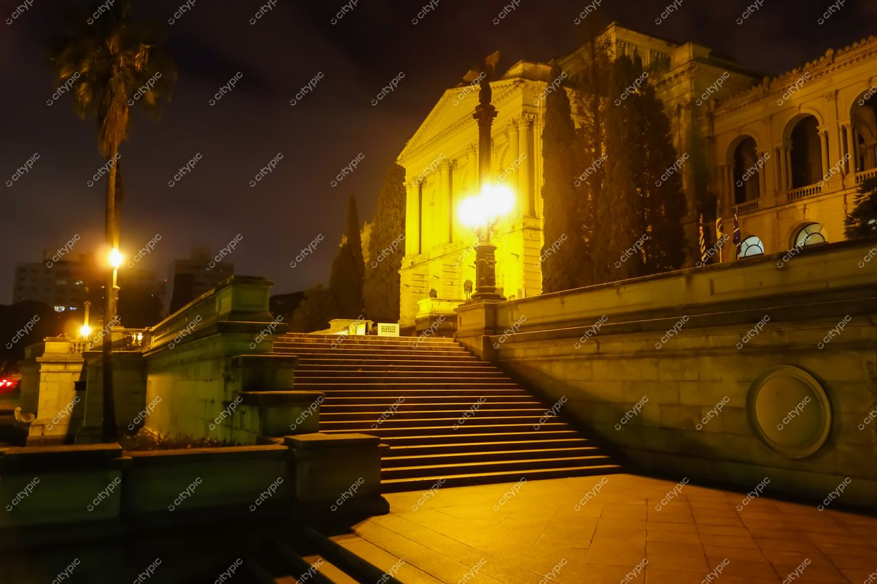 São Paulo, São Paulo, fachada de edifício iluminado à noite com vegetação e tráfego urbano ao fundo