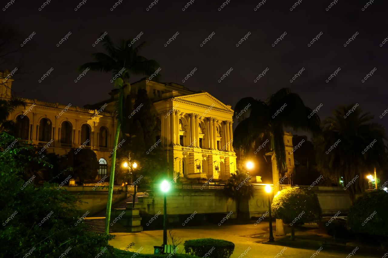 São Paulo, São Paulo, edifício histórico iluminado à noite com vegetação exuberante e céu nublado ao fundo