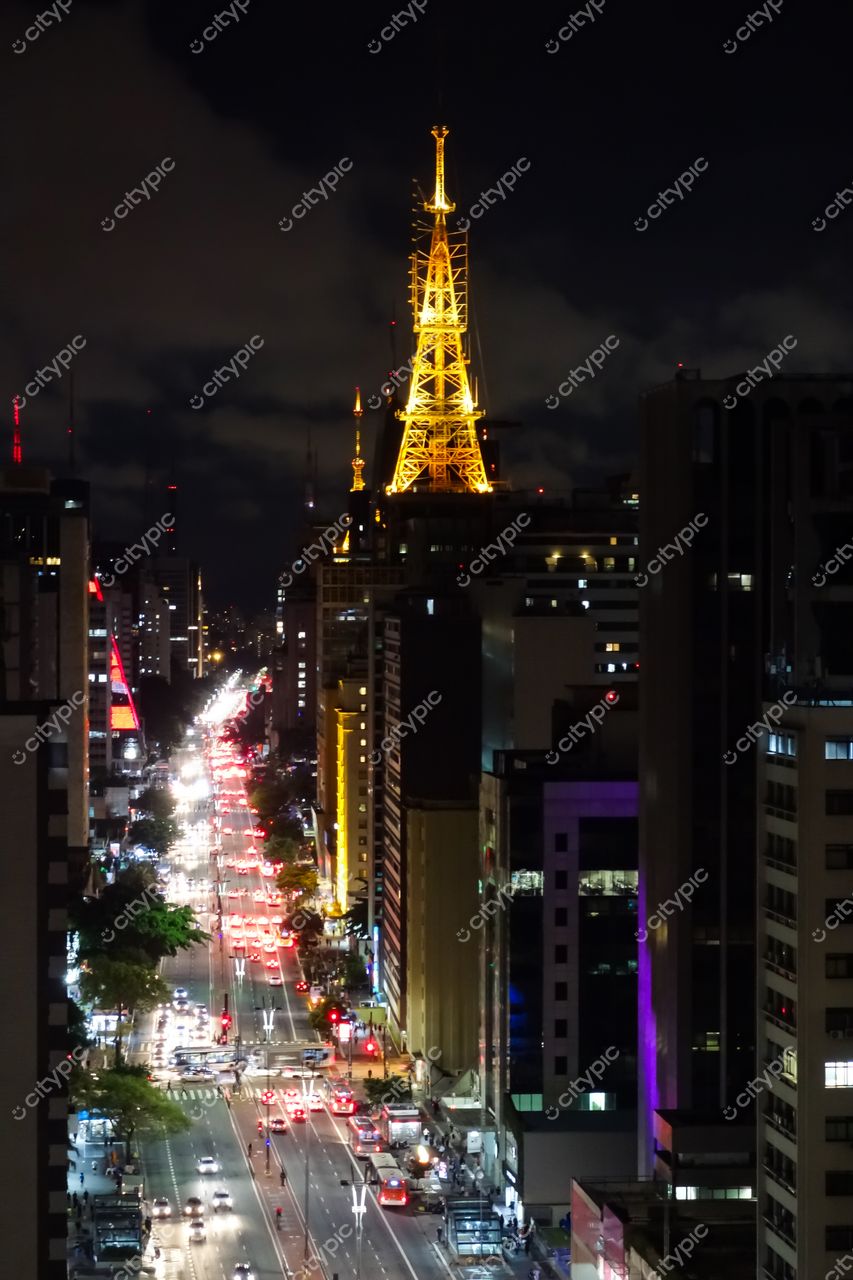 São Paulo, São Paulo, vista noturna da Avenida Paulista com a Torre do Banespa iluminada em amarelo e tráfego intenso