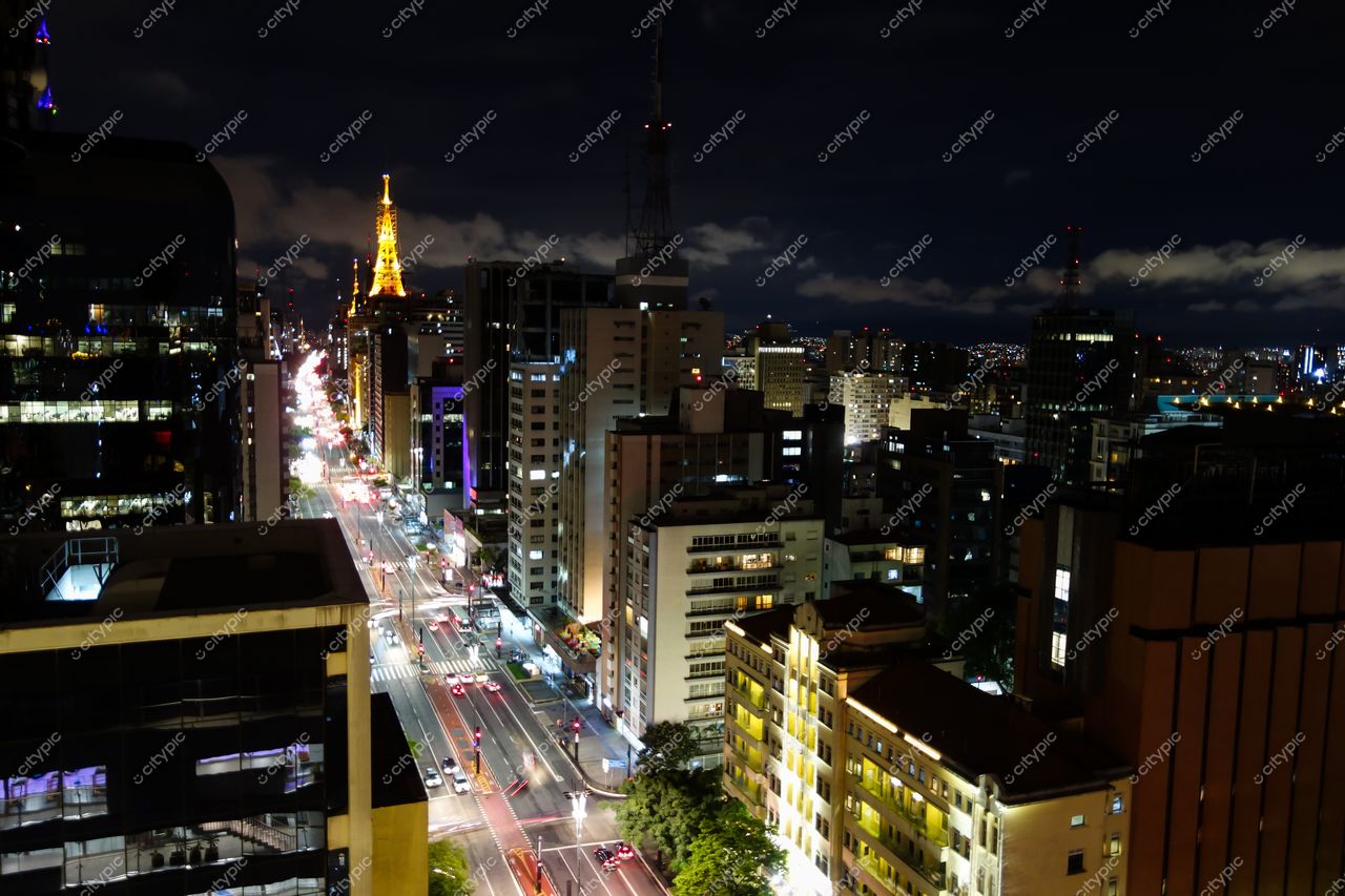 São Paulo, São Paulo, vista noturna com tráfego intenso e torre iluminada em meio a edifícios altos e nuvens