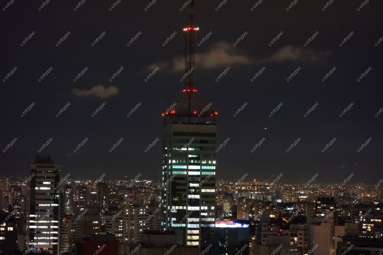 São Paulo, São Paulo, vista noturna com edifício iluminado em vermelho e luzes urbanas contrastantes na metrópole