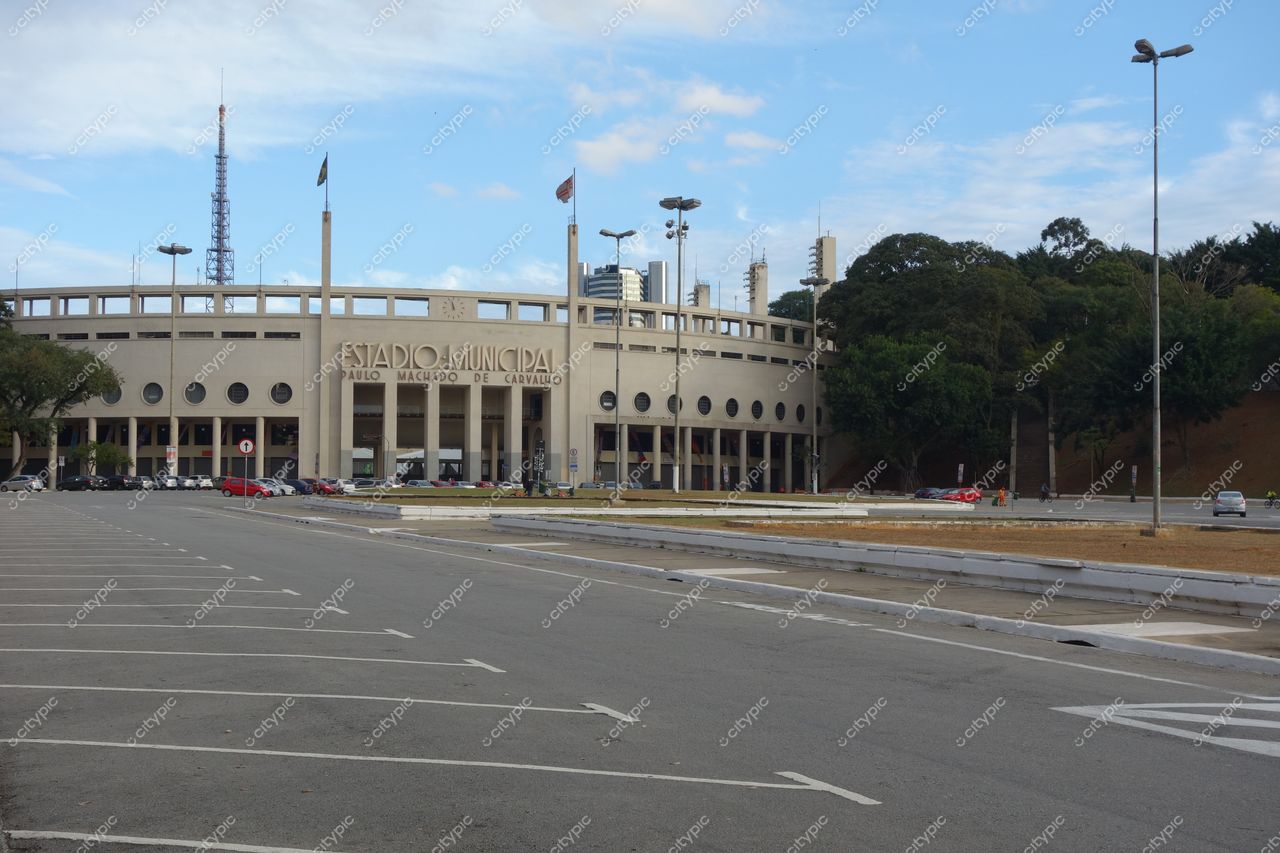 Estádio do Pacaembu em São Paulo com fachada arquitetônica, estacionamento vazio e céu parcialmente nublado durante a manhã