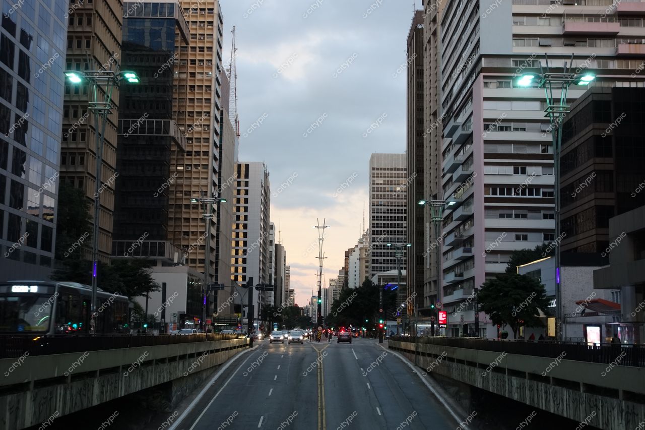 São Paulo, São Paulo, avenida larga com edifícios modernos e tradicionais ao crepúsculo, iluminação verde-azulada e tráfego visível