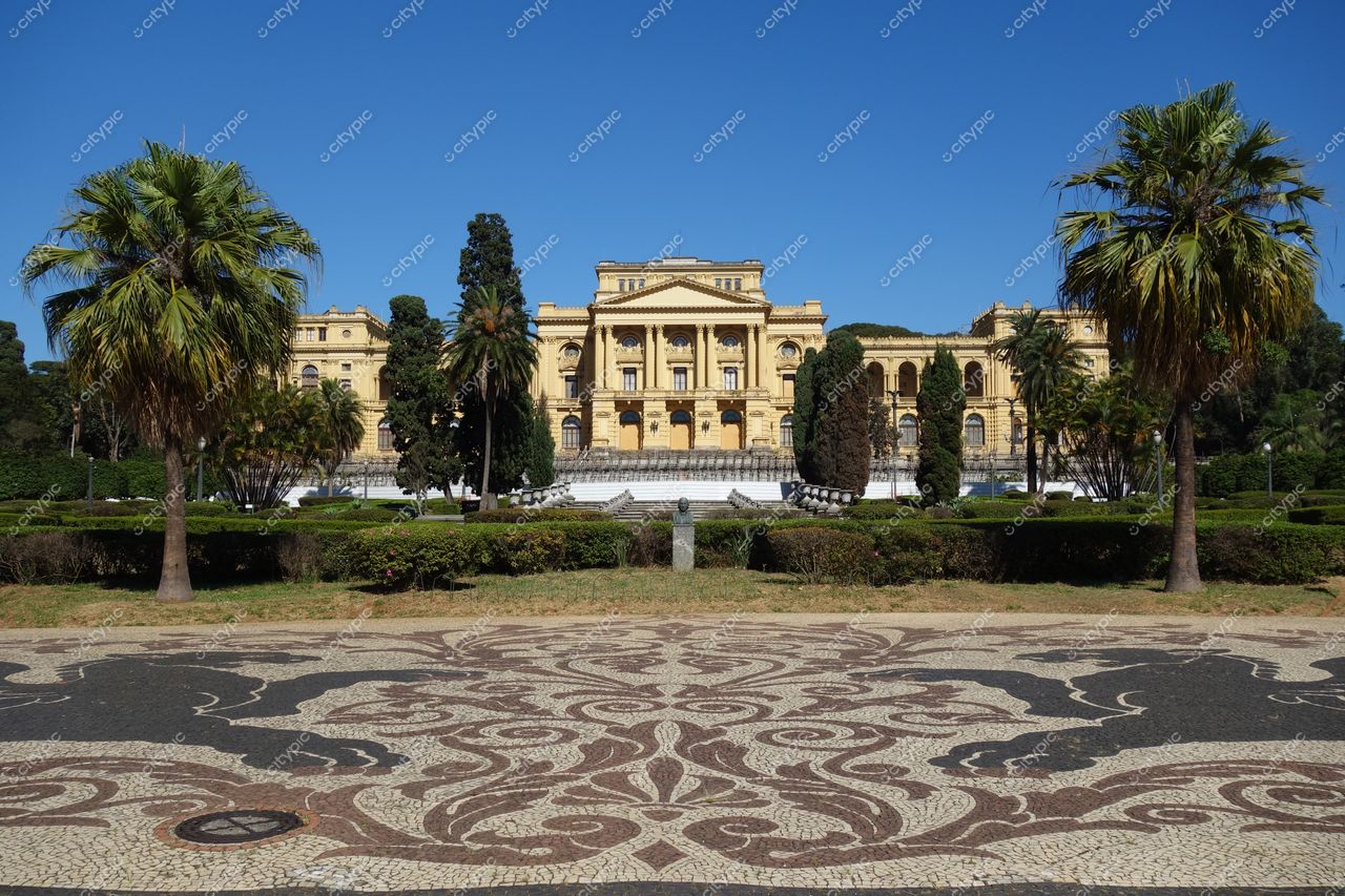 São Paulo, São Paulo, fachada do Museu Nacional em dia ensolarado com vegetação exuberante e mosaico no chão