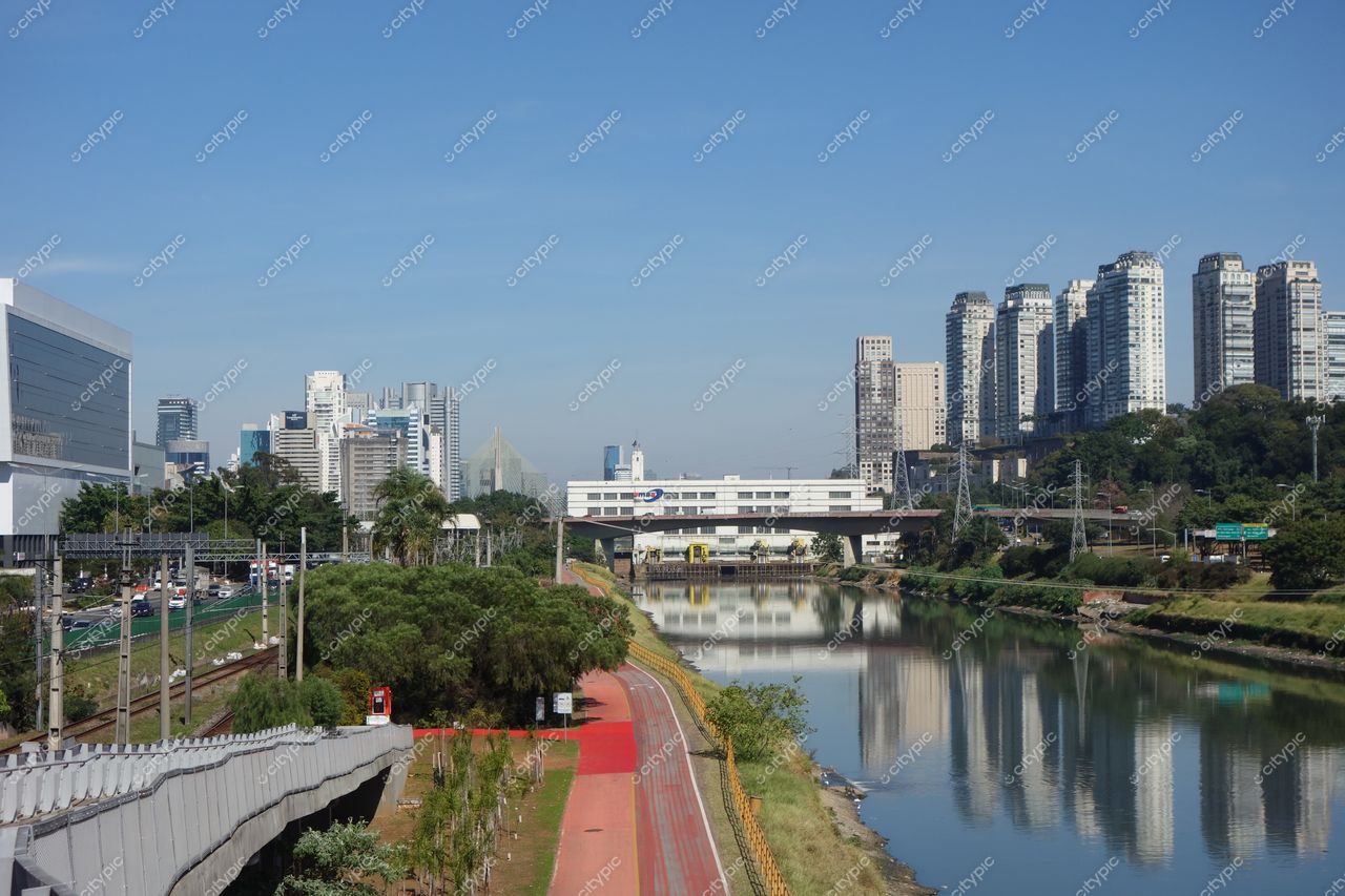 São Paulo, São Paulo, panorama urbano com arranha-céus modernos e vegetação à margem do rio sob céu azul claro