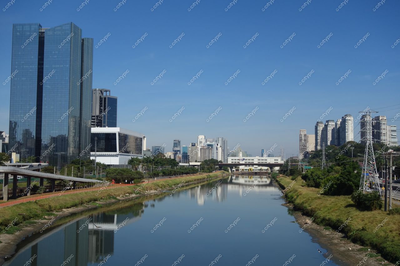 São Paulo, São Paulo, panorama urbano com arranha-céu de vidro e vegetação ao longo do rio em dia claro