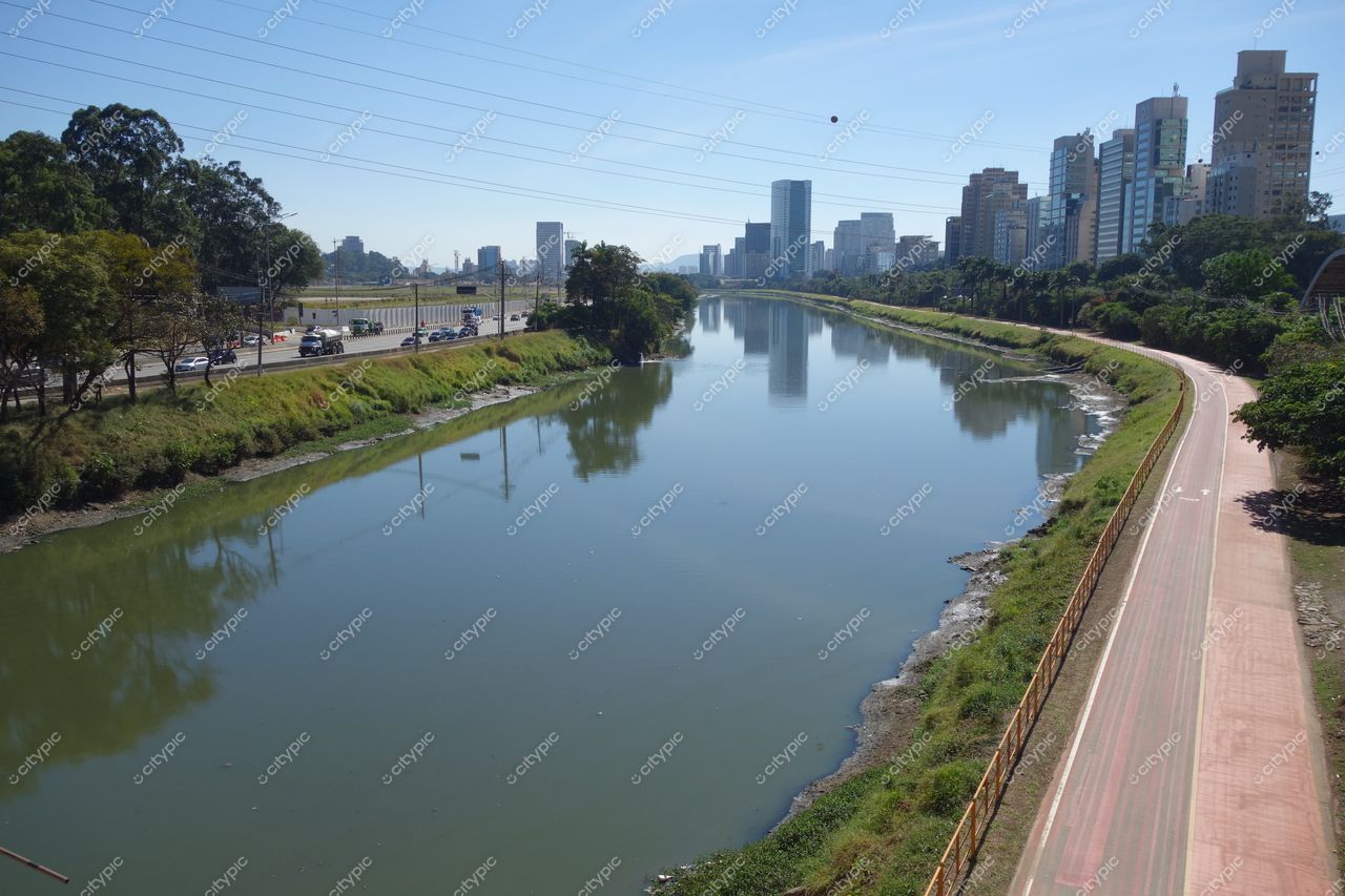 São Paulo, São Paulo, vista do rio com edifícios altos ao fundo e ciclovia à direita em dia ensolarado