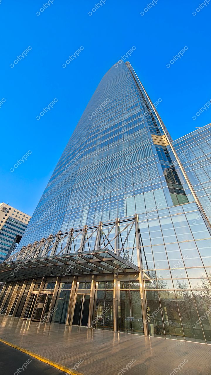 Costanera Center, Santiago em manhã clara com reflexos do céu azul e vegetação esparsa na base urbana
