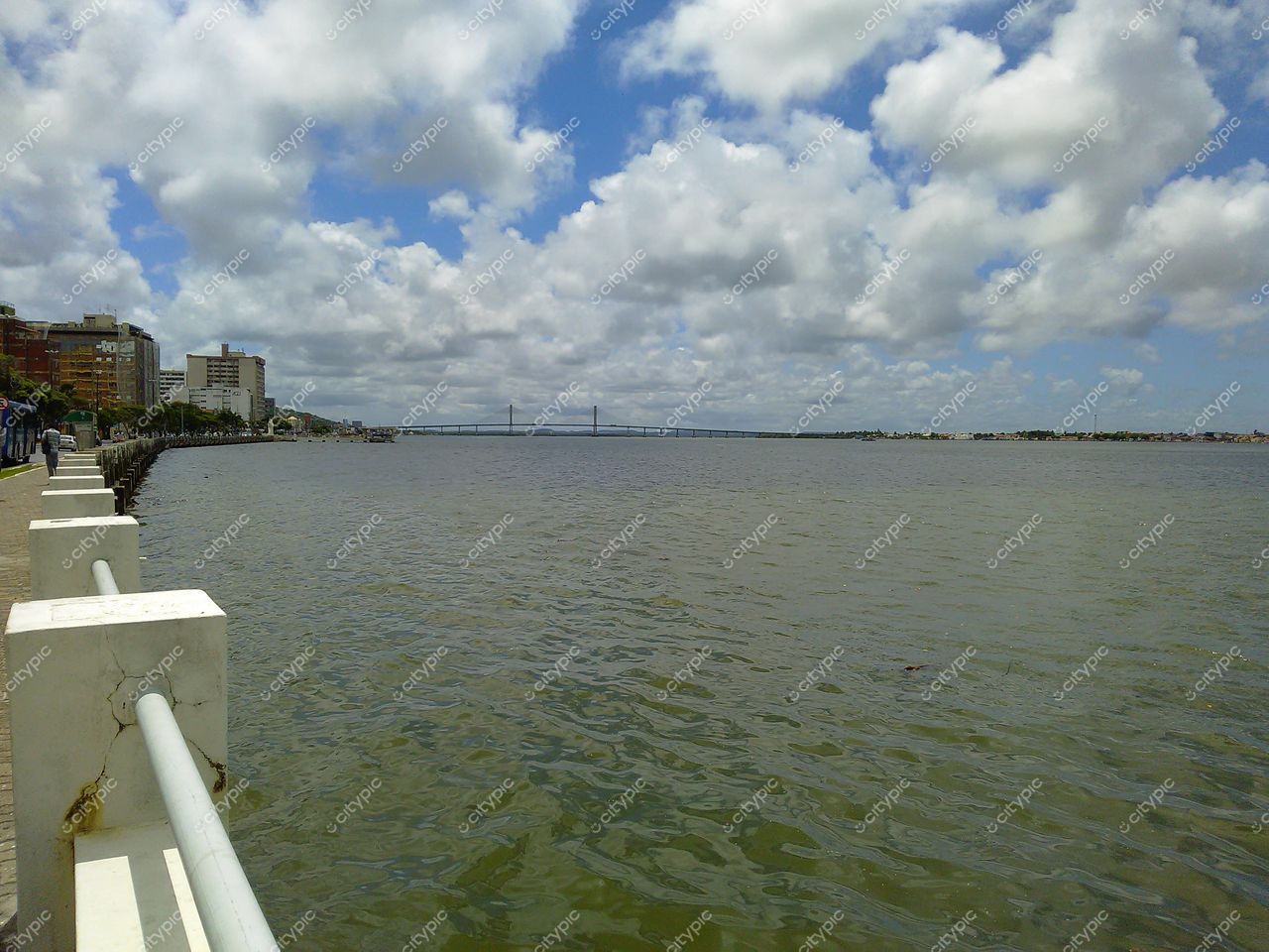 Aracaju, Sergipe vista da orla com calçadão, edifícios baixos e ponte ao fundo em dia nublado