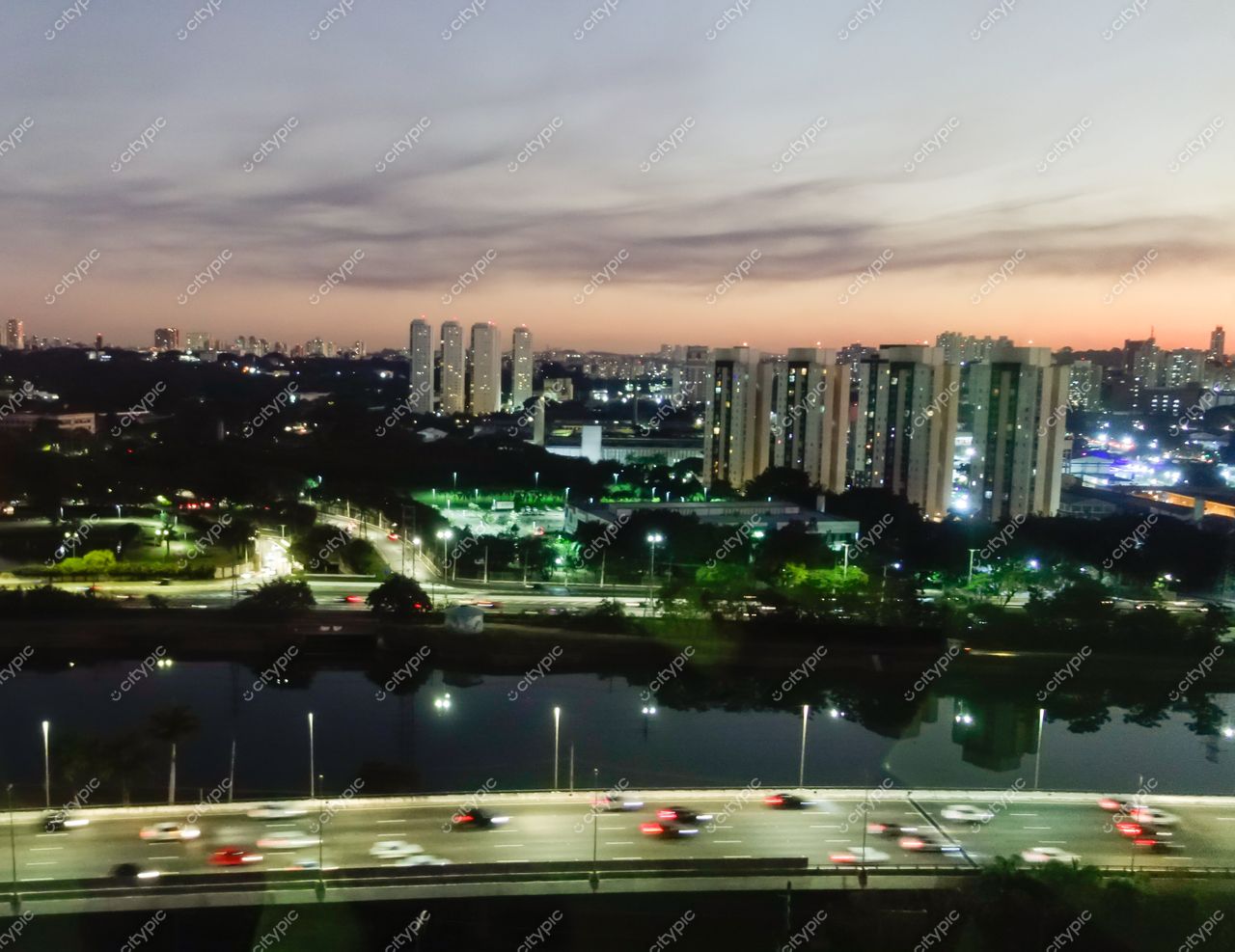 São Paulo, São Paulo, vista urbana ao entardecer com rodovia movimentada e edifícios altos cercados por vegetação
