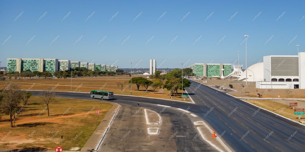 Esplanada dos Ministérios em Brasília com céu azul, edifícios verdes, Igrejinha de Fátima e tráfego urbano visível