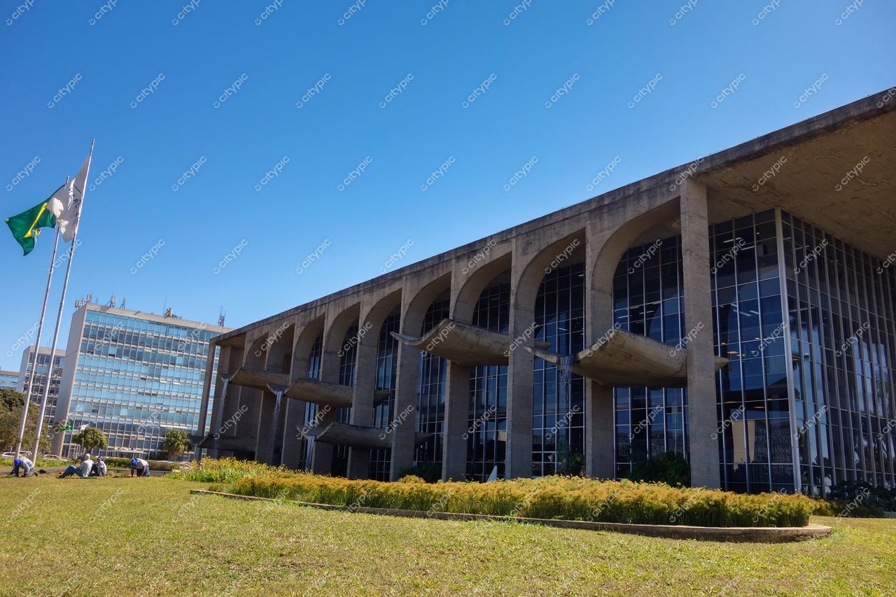 Palácio do Itamaraty em Brasília com arquitetura moderna, céu claro e pessoas descansando em área verde ao redor