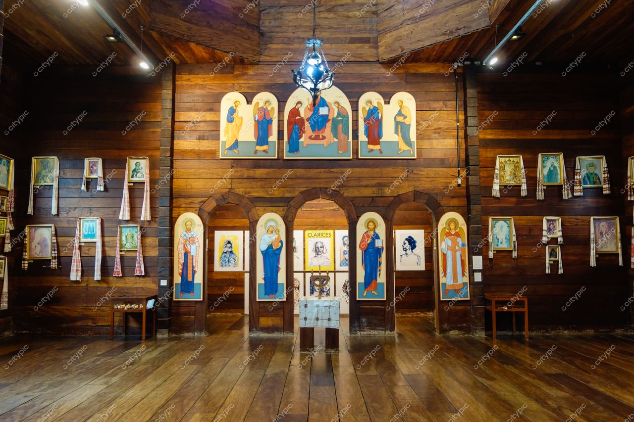 Bosque Alemão em Curitiba com interior de espaço cultural iluminado, paredes de madeira e iconografias religiosas visíveis