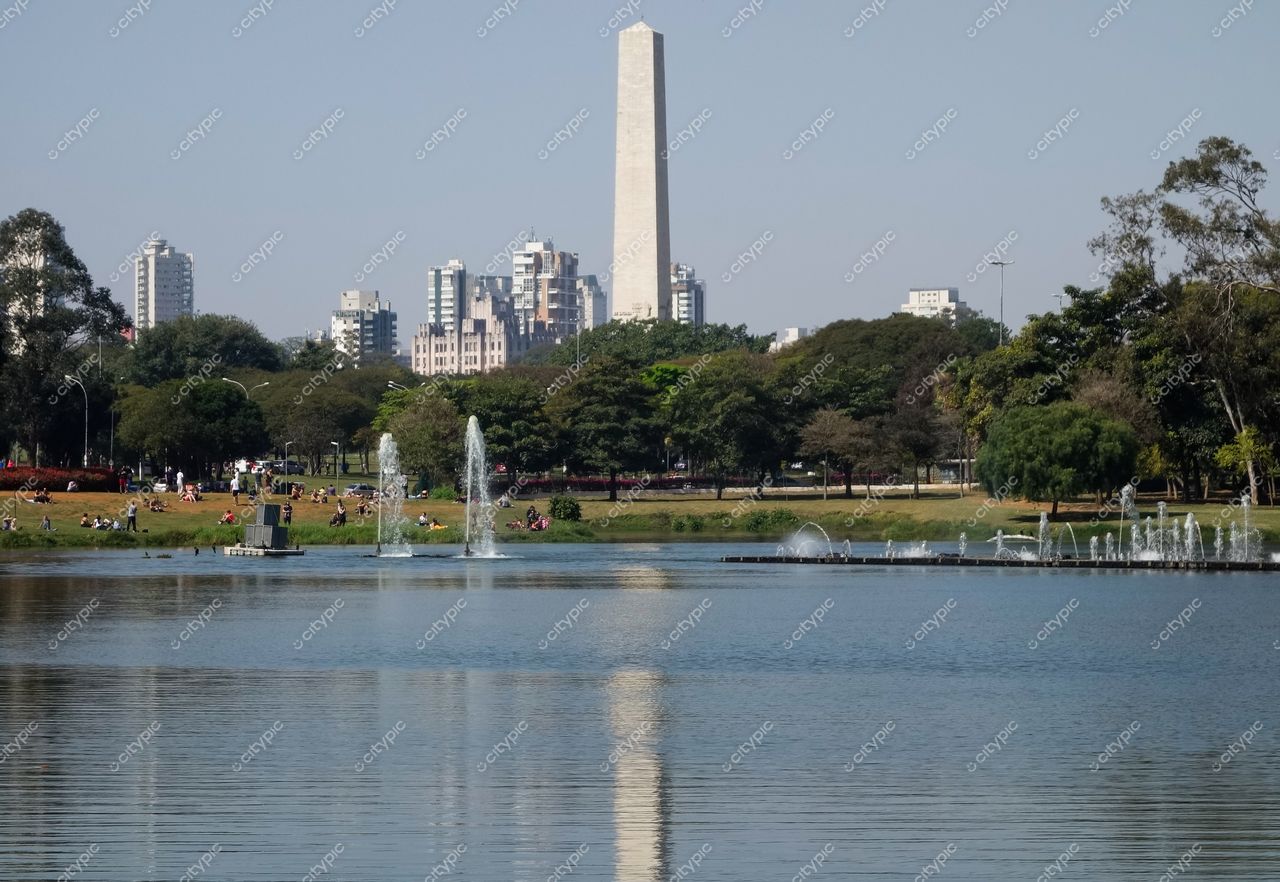 São Paulo, São Paulo, lago sereno com vegetação densa e monumento imponente entre edifícios em dia claro