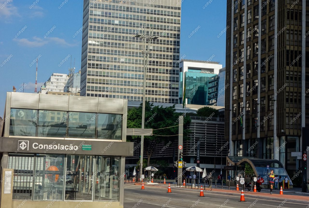 Avenida Paulista em São Paulo com estação de metrô Consolação, céu azul e tráfego visível em dia ensolarado
