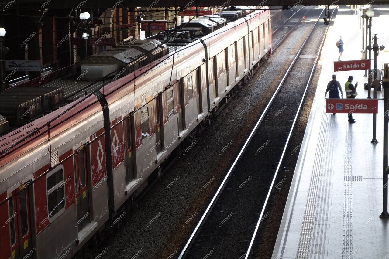 Estação da Luz em São Paulo com trem prateado e vermelho, iluminação suave e arquitetura histórica visível na plataforma