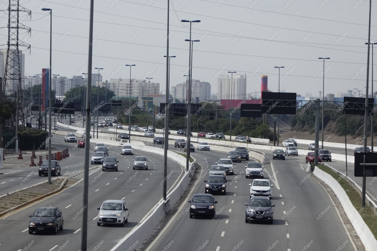 São Paulo, São Paulo, via urbana movimentada com céu parcialmente nublado e vegetação ao longo da estrada