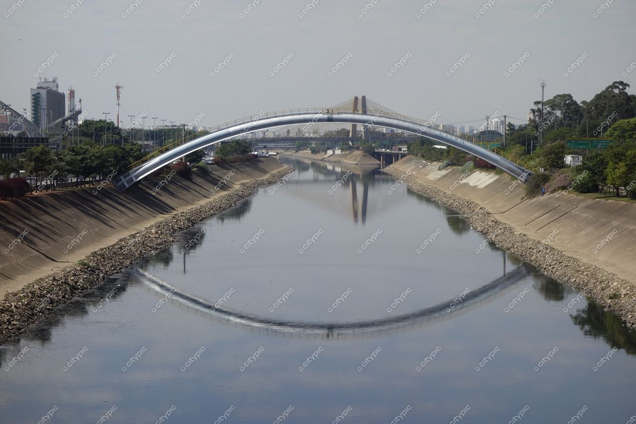 São Paulo, São Paulo, vista da ponte arqueada moderna refletindo no canal com vegetação e edifícios contemporâneos ao fundo