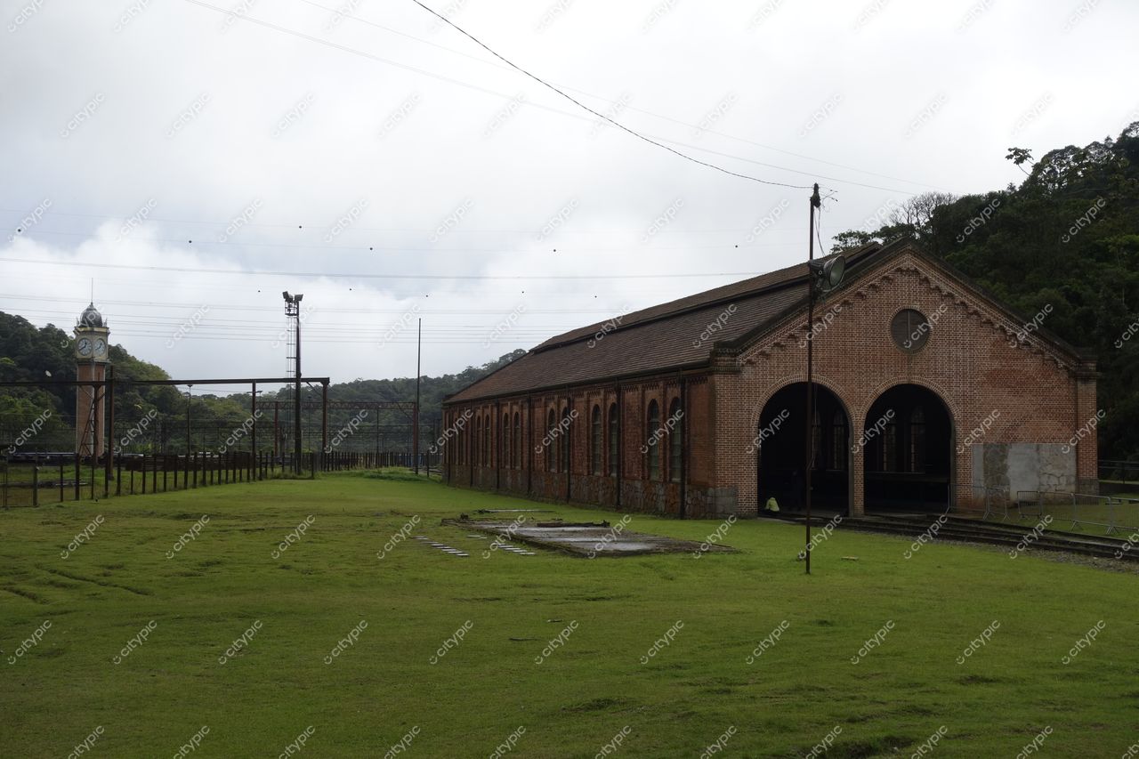 Paranapiacaba, São Paulo, antigo edifício de tijolos com torre de relógio em dia nublado e vegetação montanhosa