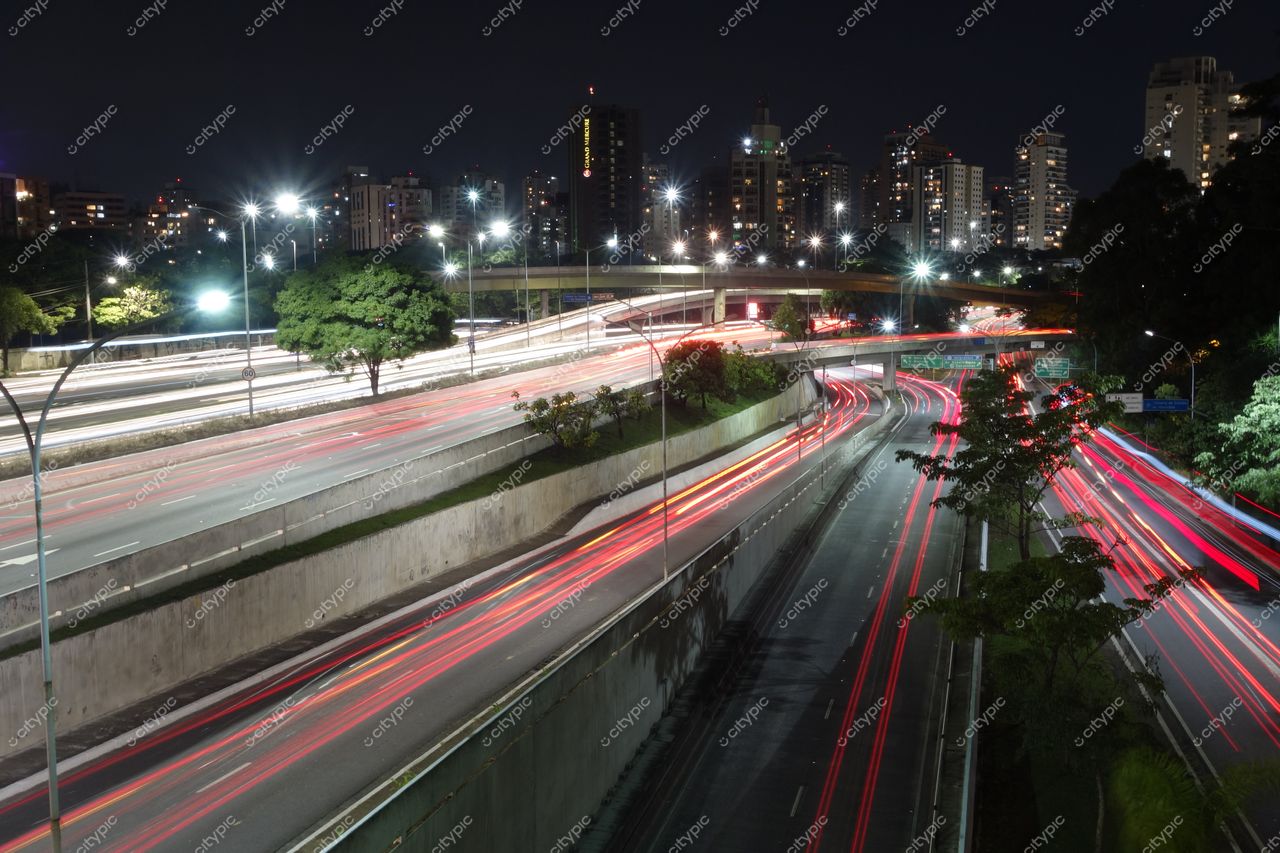 São Paulo, São Paulo, cruzamento noturno movimentado com faixas de tráfego e edifícios iluminados ao fundo