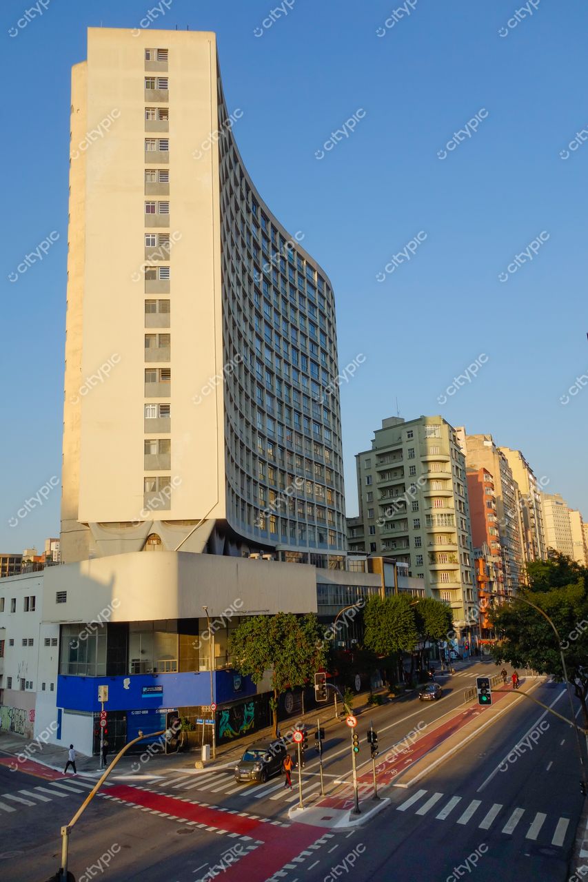 Elevado Presidente João Goulart em São Paulo com edifício curvo e iluminação amarelada em dia claro e tráfego leve