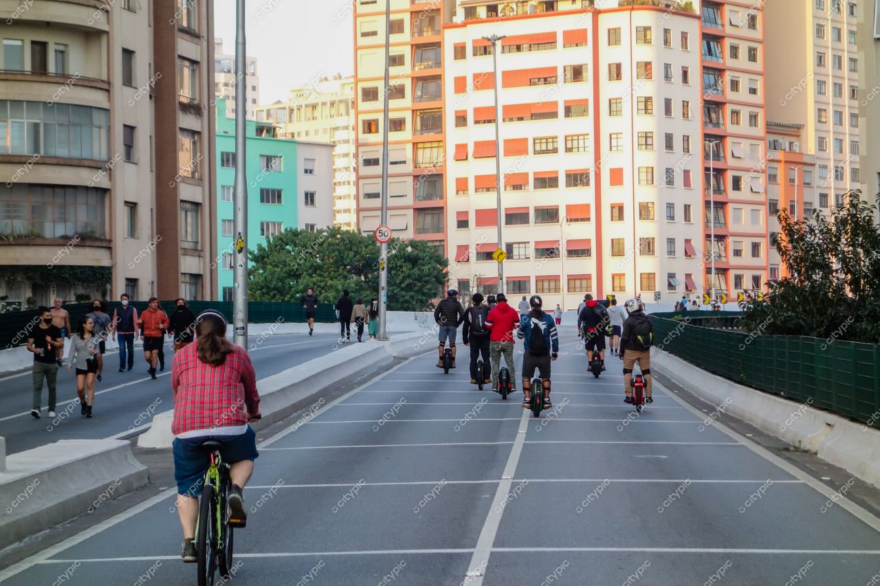 Elevado Presidente João Goulart em São Paulo com ciclistas e pedestres sob luz suave do final da tarde
