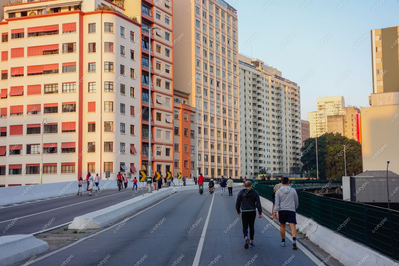 Elevado Presidente João Goulart em São Paulo ao entardecer com iluminação suave e movimentação de pedestres e ciclistas