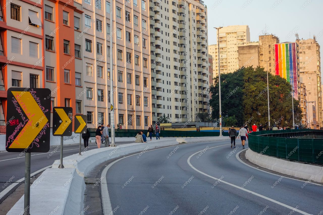 Elevado Presidente João Goulart em São Paulo com pôr do sol, placas de sinalização e mural colorido ao fundo