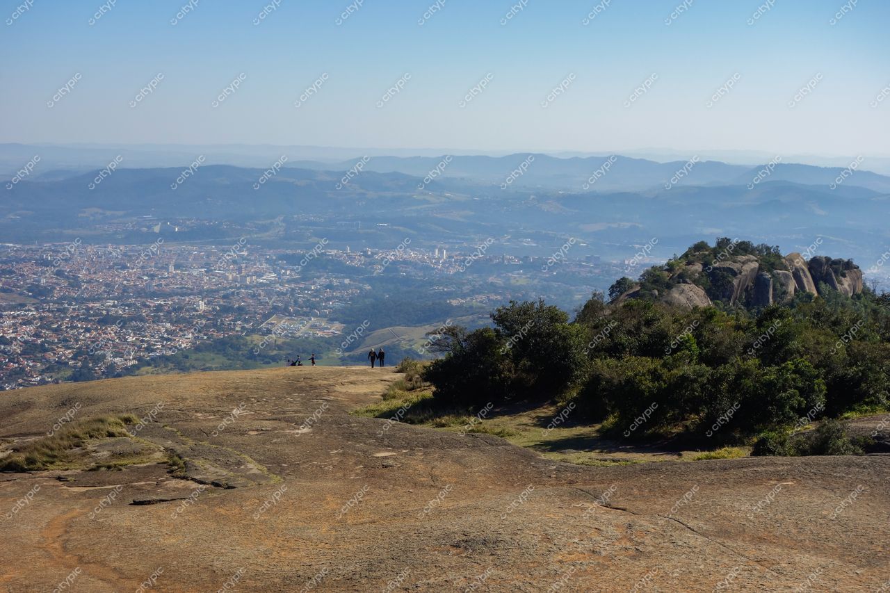 Atibaia, São Paulo vista panorâmica em dia claro com vegetação verdejante e pessoas sobre rochas elevadas