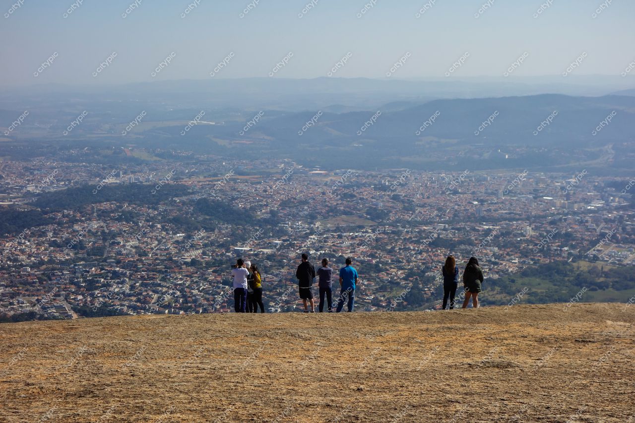 Atibaia, São Paulo, grupo de pessoas no mirante da Pedra Grande com vista urbana e montanhas ao fundo em dia ensolarado