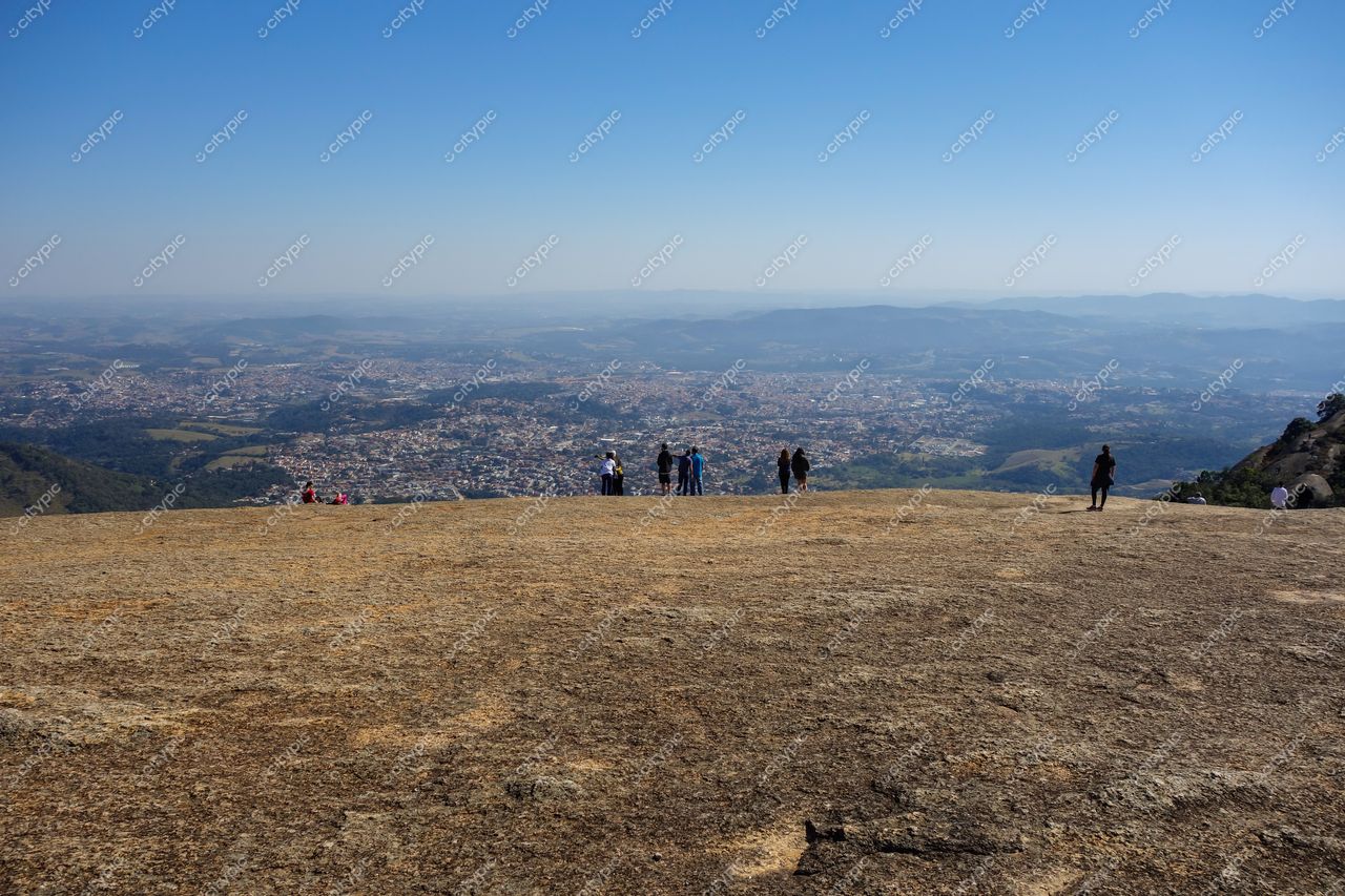 Atibaia, São Paulo vista panorâmica do alto de rocha com pessoas e paisagem urbana e rural sob céu azul claro