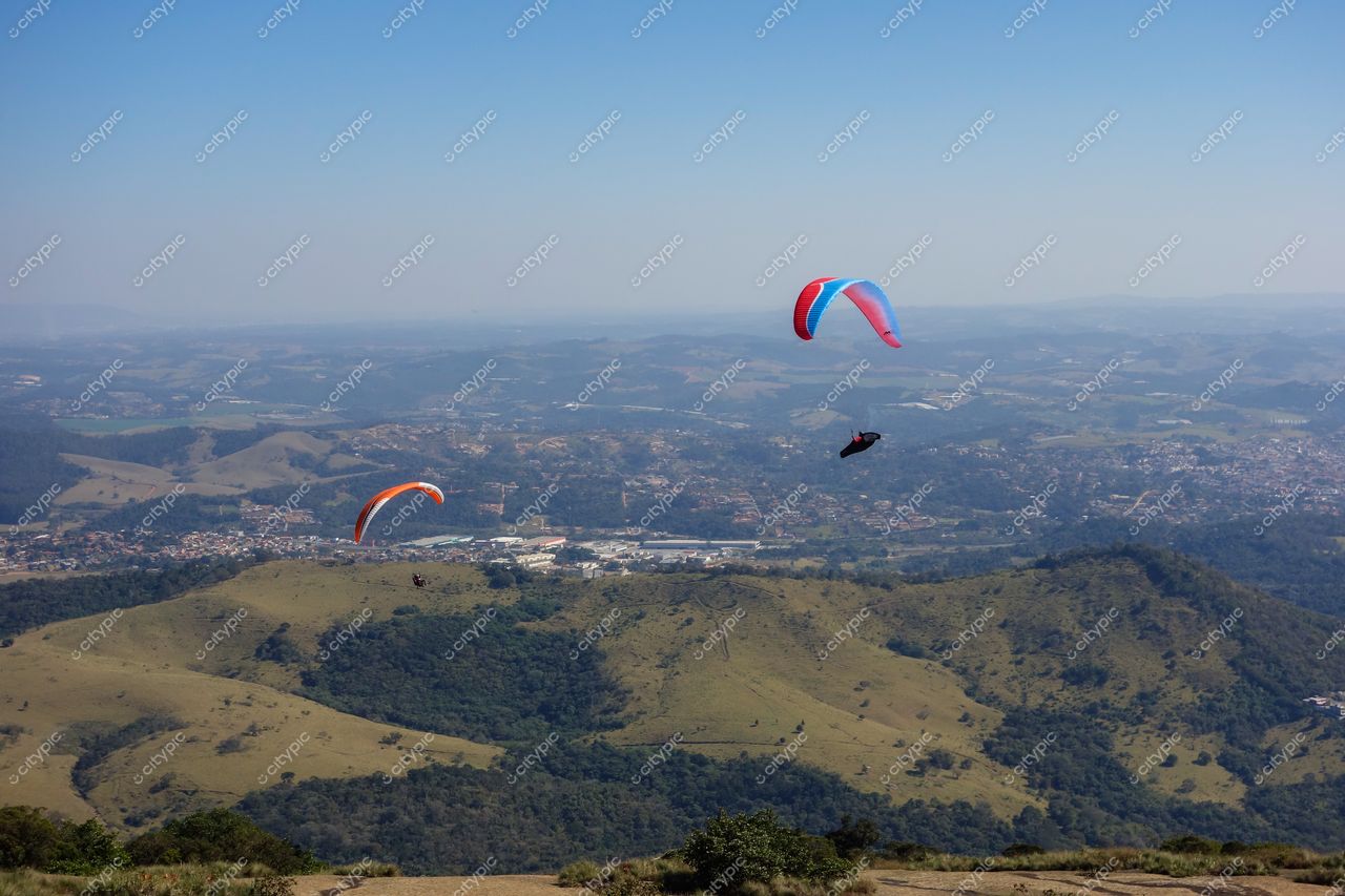 Atibaia, São Paulo, parapentes coloridos sobre montanhas verdes e áreas urbanas em dia ensolarado com céu limpo
