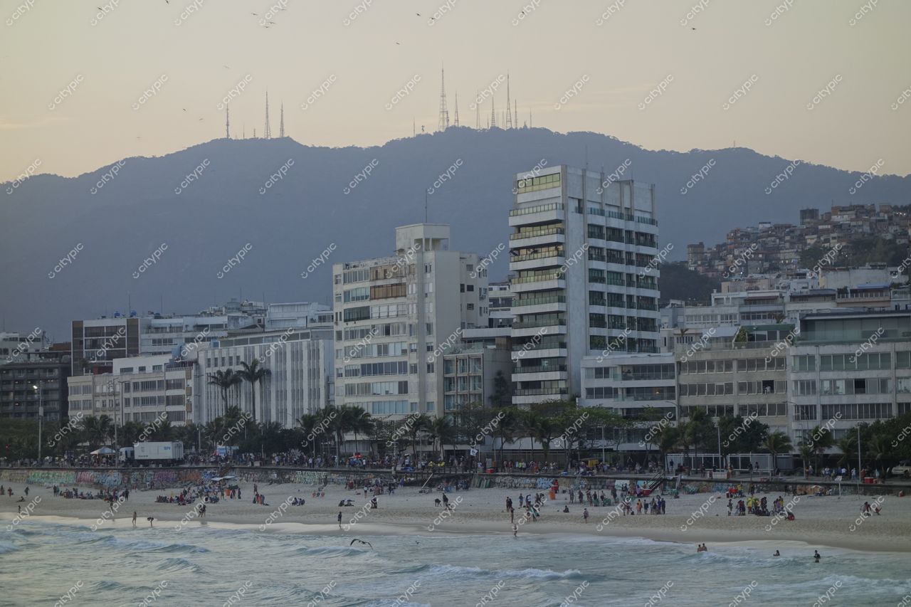 Rio de Janeiro, Rio de Janeiro, vista da orla ao entardecer com frequentadores na praia e montanhas ao fundo