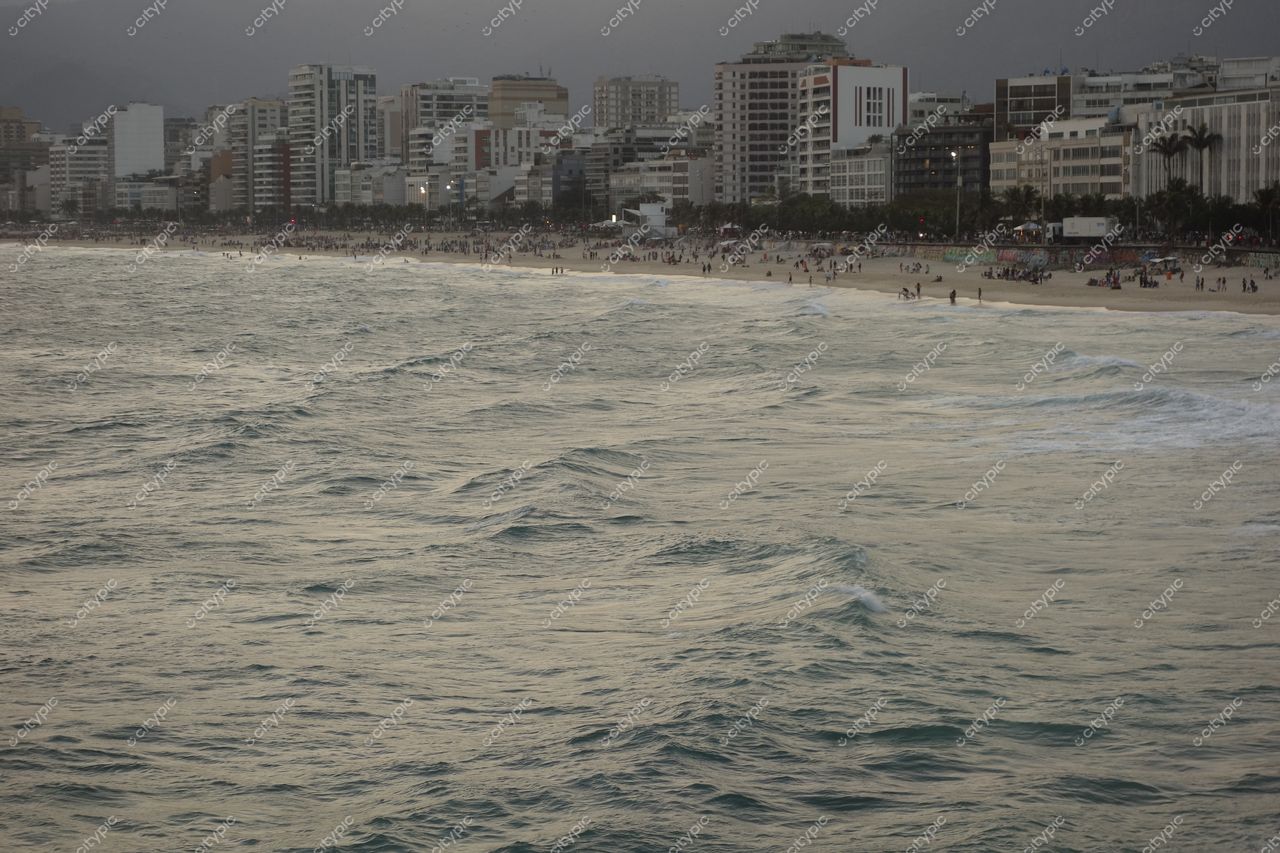 Rio de Janeiro, Rio de Janeiro, vista da praia ao entardecer com ondas suaves e edifícios modernos ao fundo