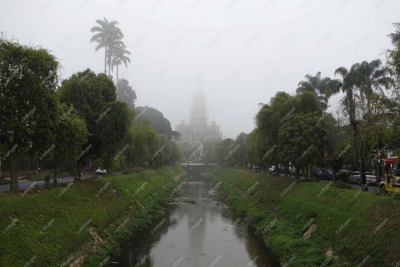 Petrópolis, Rio de Janeiro vista nublada com neblina, riacho e vegetação densa ao fundo com arquitetura imponente