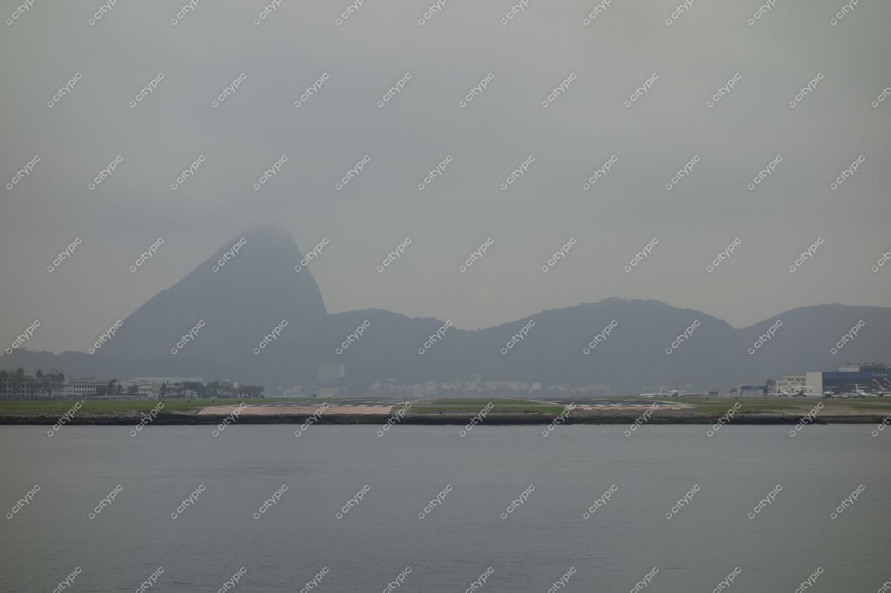 Rio de Janeiro, Rio de Janeiro com vista nublada e montanhas icônicas ao fundo, vegetação baixa e arquitetura moderna