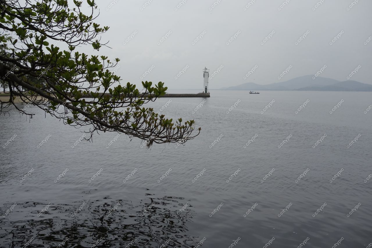 Ilha de Paquetá, Rio de Janeiro com vista da baía tranquila e farol branco sob céu nublado e vegetação verde