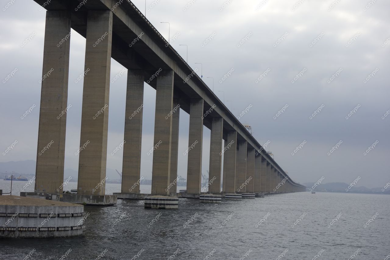 Rio de Janeiro, Rio de Janeiro, ponte de concreto sobre corpo d’água com céu nublado e montanhas ao fundo
