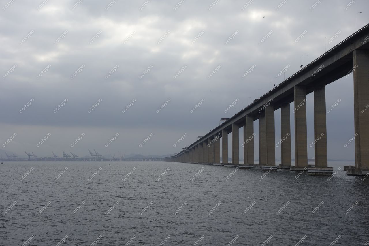 Rio de Janeiro, Rio de Janeiro, ponte suspensa sobre baía com colunas visíveis e céu nublado ao fundo