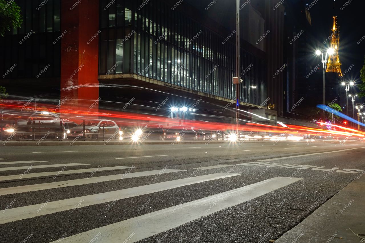 São Paulo, São Paulo, movimentada rua noturna com carros em movimento e reflexos de edifício moderno e Torre Eiffel