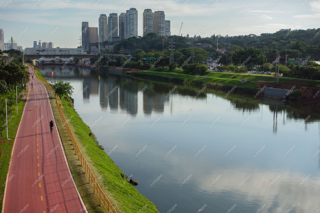 São Paulo, São Paulo, ciclovia vermelha à beira do rio com edifícios modernos e vegetação ao amanhecer