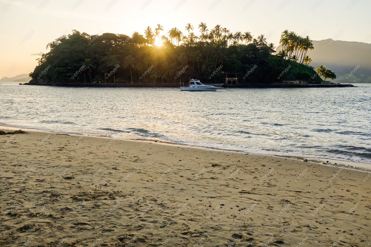 Ilhabela, São Paulo vista serena da praia com areia dourada e barco de passeio ao pôr do sol