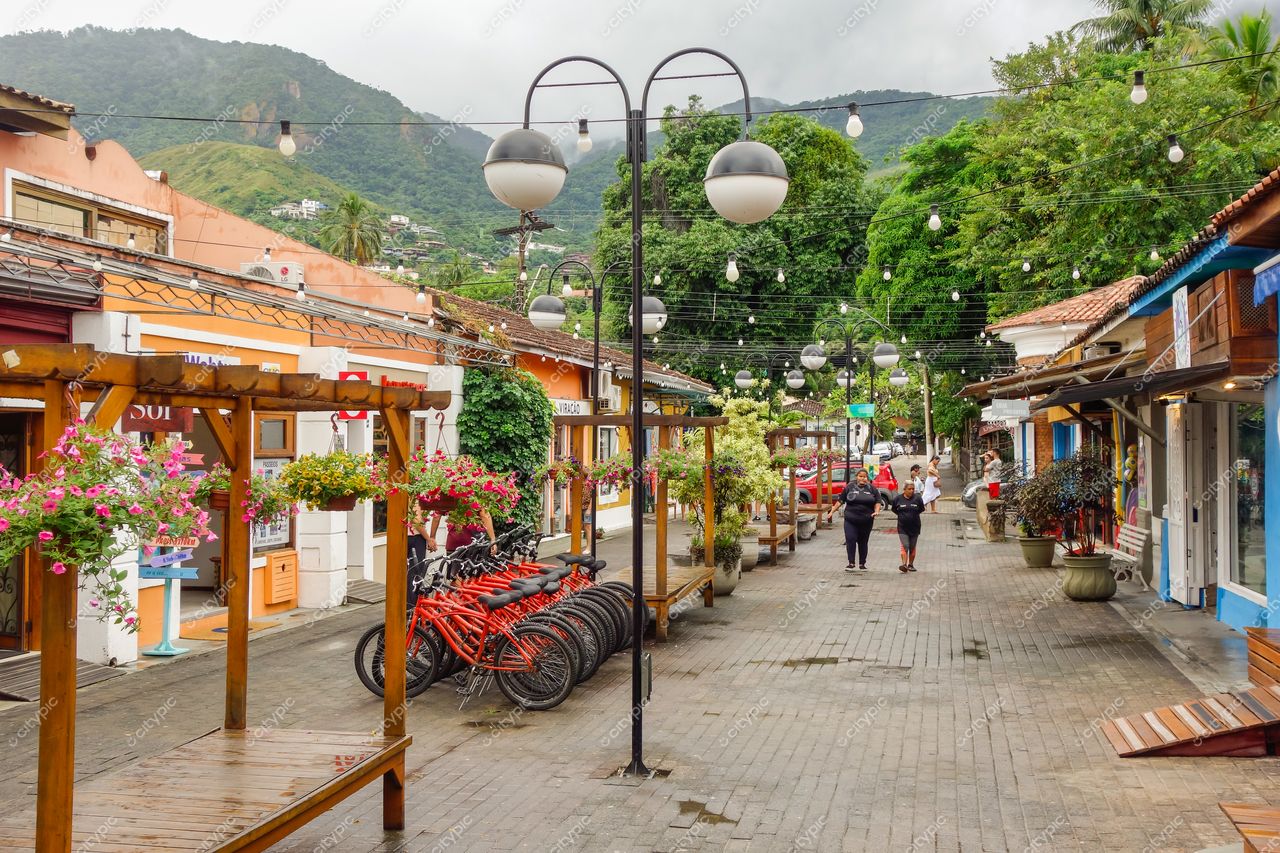 Ilhabela, São Paulo, rua tranquila com casas coloridas, calçamento de pedras e vegetação montanhosa ao fundo