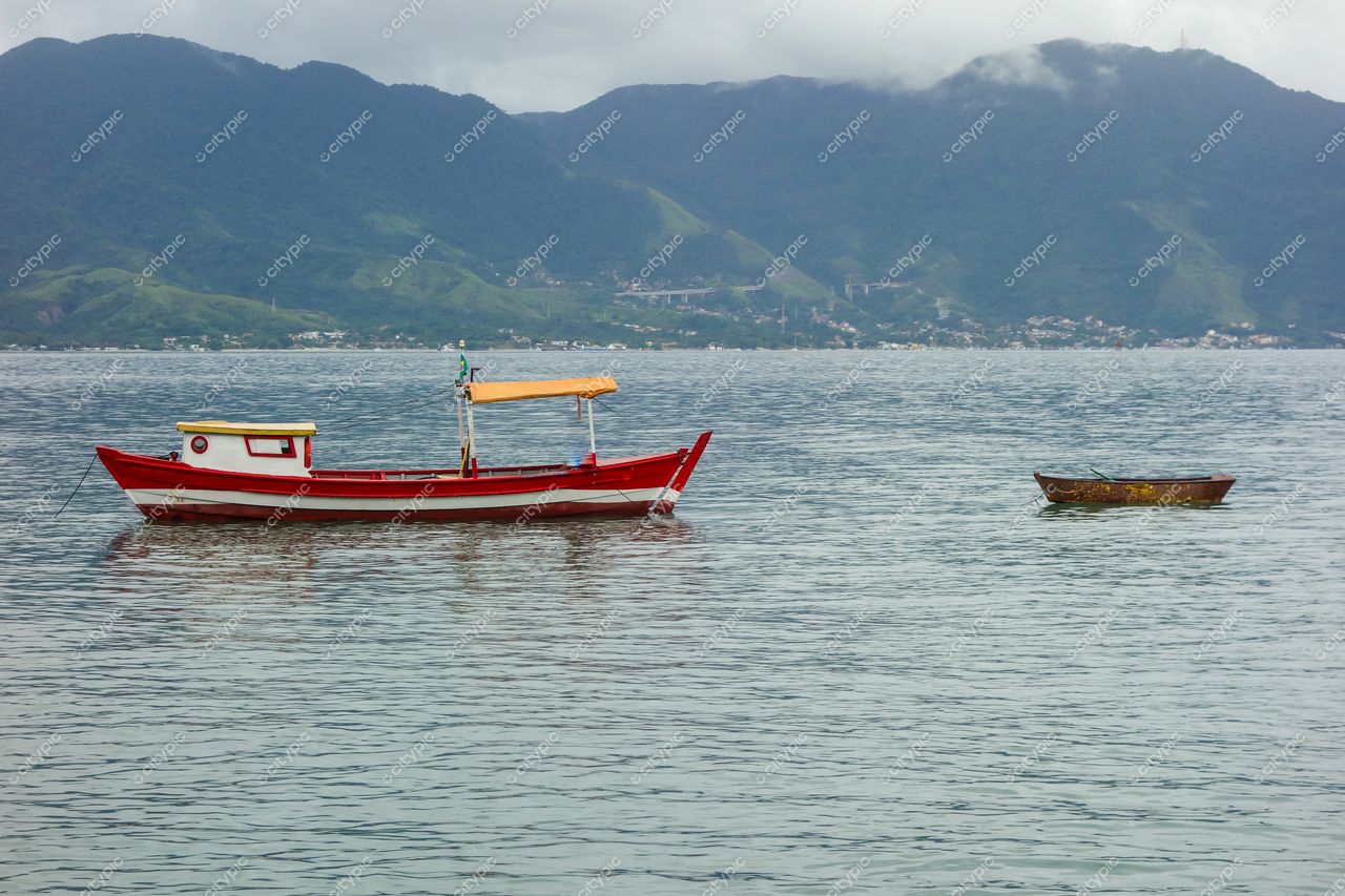 Ilhabela, São Paulo com barco de pesca vermelho ancorado em águas calmas e montanhas verdes ao fundo