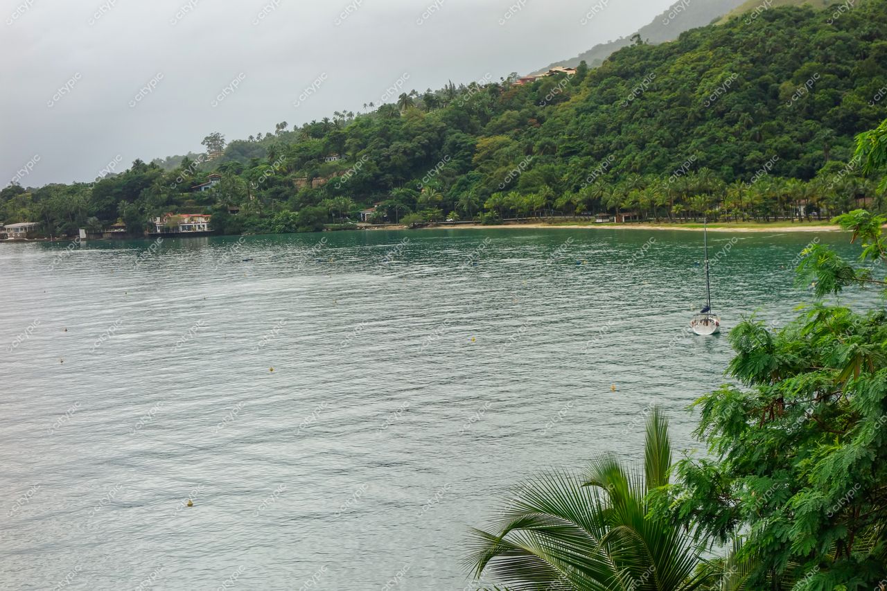Ilhabela, São Paulo vista em dia nublado com casas à beira-mar e vegetação densa ao fundo