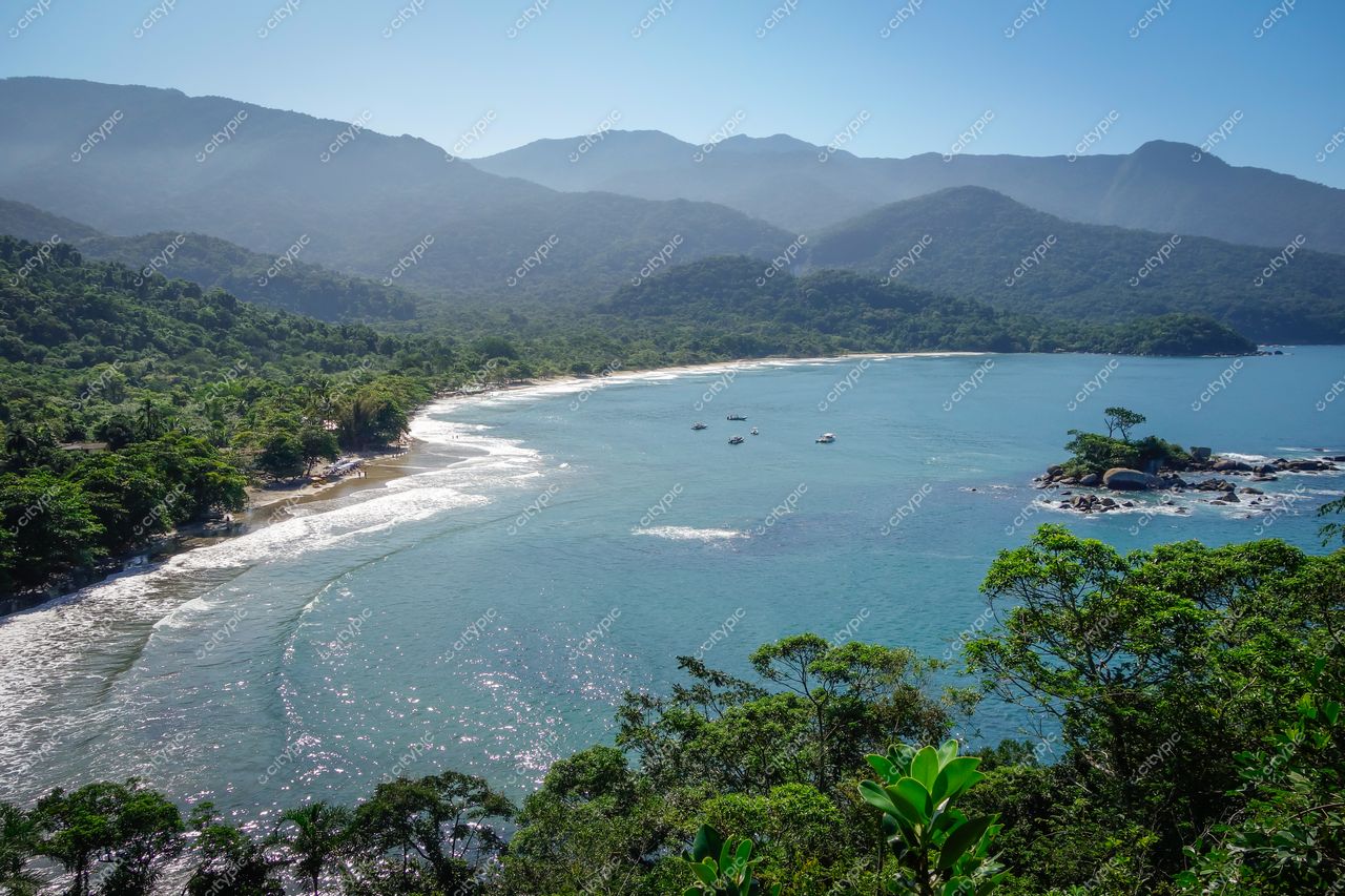 Ilhabela, São Paulo com baía tranquila e águas azuladas ao amanhecer, montanhas verdes e pequenas embarcações ancoradas