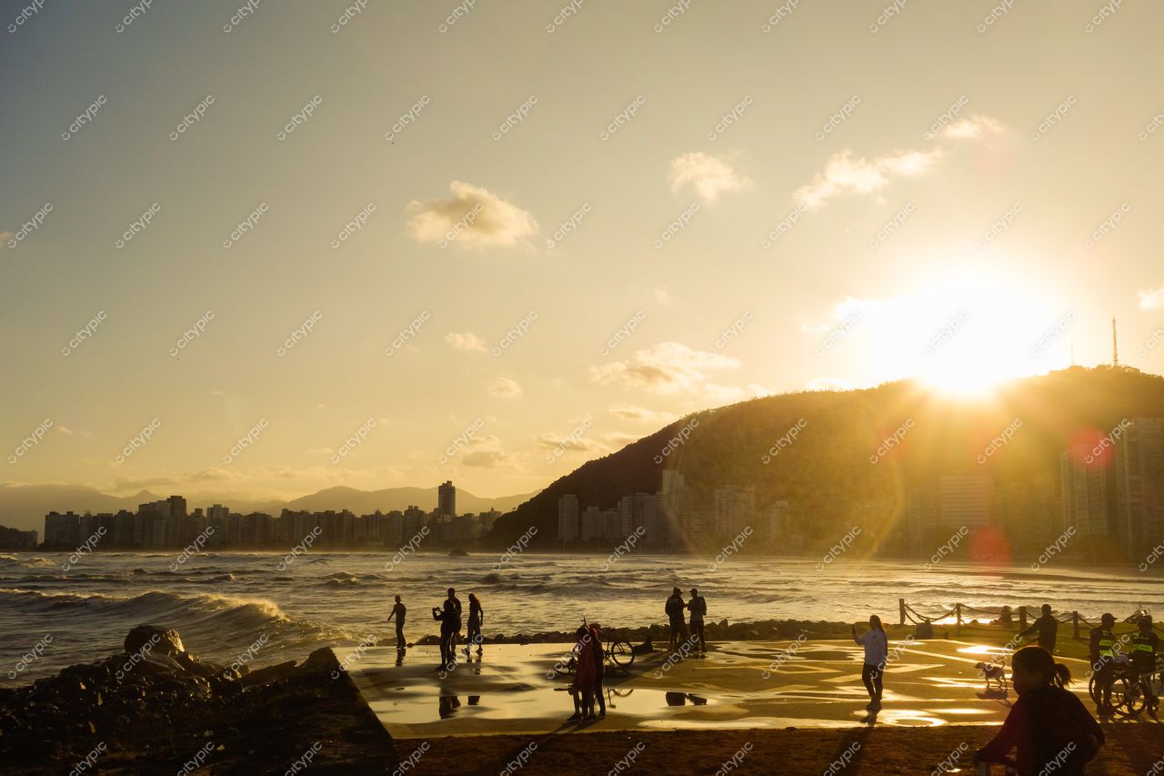 Santos, São Paulo, pôr do sol com luz dourada refletindo na água e montanhas ao fundo na praia urbana