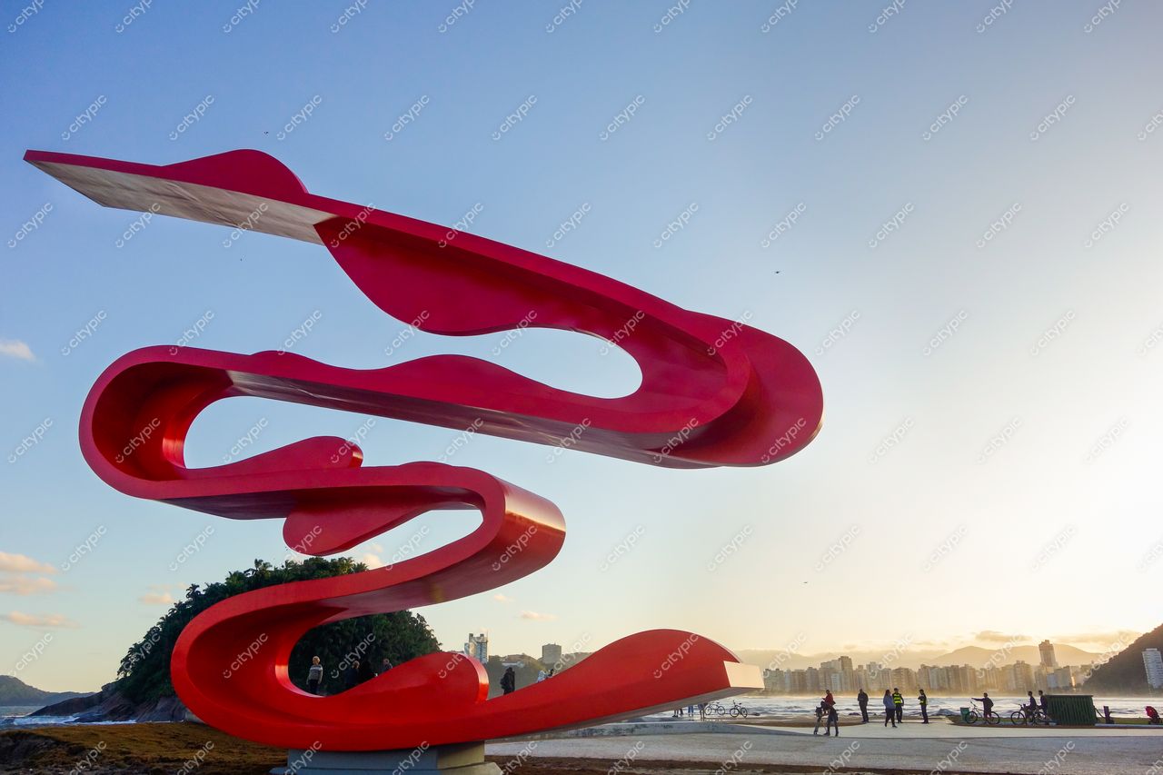 Monumento Tomie Ohtake em Santos com escultura vermelha ao pôr do sol e orla da praia ao fundo
